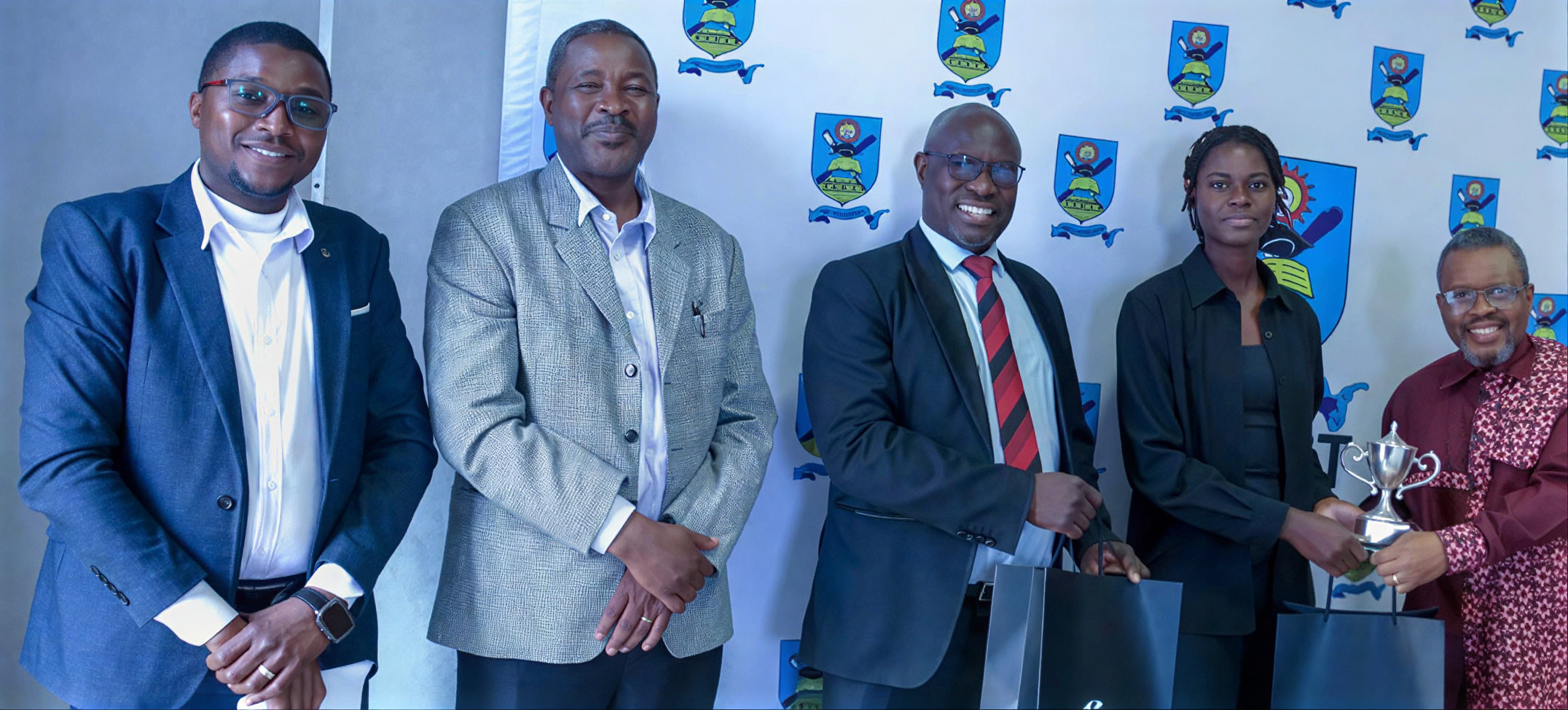Group of professionals at an award ceremony in front of institutional crest