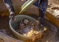 Artisanal miner sifting crushed ore for gold particles at a small‑scale mine in Zimbabwe.