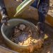 Artisanal miner sifting crushed ore for gold particles at a small‑scale mine in Zimbabwe.
