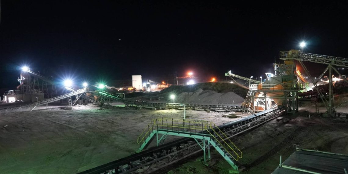 Night view of a diamond mining site with illuminated conveyor belts and processing plants.