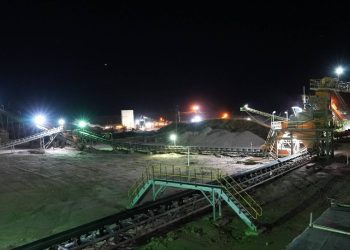 Night view of a diamond mining site with illuminated conveyor belts and processing plants.