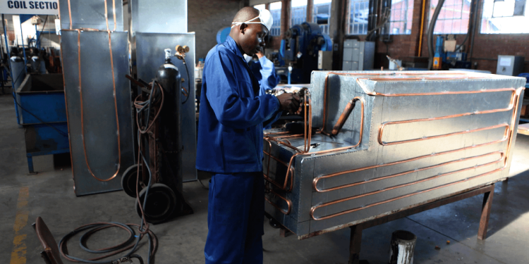 Factory worker assembling metal equipment inside a workshop in Harare.