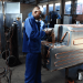 Factory worker assembling metal equipment inside a workshop in Harare.