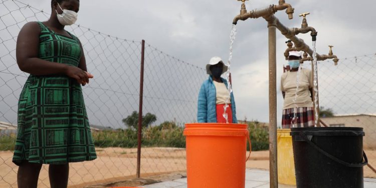 Residents collect water at a community water point in Zimbabwe.
