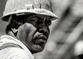 Close-up of a miner wearing a hard hat at an industrial site.