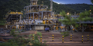 Industrial graphite processing plant with steel frameworks, pipes, and machinery in a hilly area of Cabo Delgado, Mozambique.