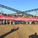 Workers stand in front of a spodumene lithium ore processing plant at the Bikita mine in Zimbabwe, holding a banner marking the project’s completion.