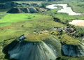 Aerial view of rounded mine waste mounds and surrounding green plains at the Manono Mine site.