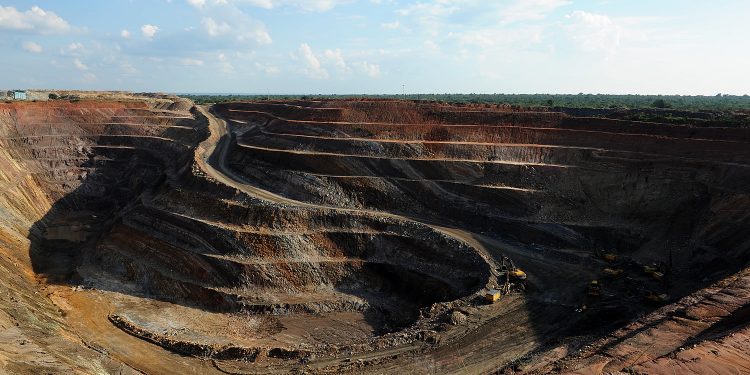 Large open‑pit copper mine with terraced levels, mining trucks, and excavators working at the bottom.