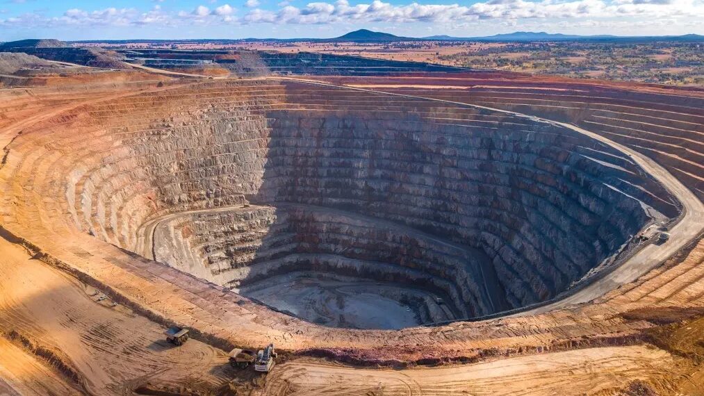 Aerial view of an open pit mine in Africa showing terraced rock walls and heavy equipment at the base