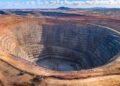 Aerial view of an open pit mine in Africa showing terraced rock walls and heavy equipment at the base