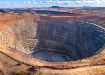 Aerial view of an open pit mine in Africa showing terraced rock walls and heavy equipment at the base