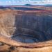 Aerial view of an open pit mine in Africa showing terraced rock walls and heavy equipment at the base