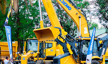 Large yellow mining and construction vehicles displayed at an outdoor trade show