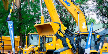Large yellow mining and construction vehicles displayed at an outdoor trade show