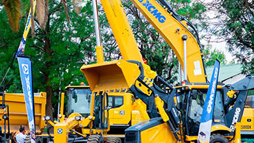 Large yellow mining and construction vehicles displayed at an outdoor trade show