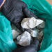 A gloved hand holds a sample of spodumene ore, a lithium-bearing mineral.