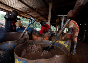 A young artisanal miner washes crushed rock containing gold in metal drums at the unlicensed mining site of Nsuaem Top in Ghana