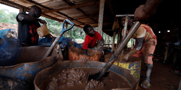 A young artisanal miner washes crushed rock containing gold in metal drums at the unlicensed mining site of Nsuaem Top in Ghana