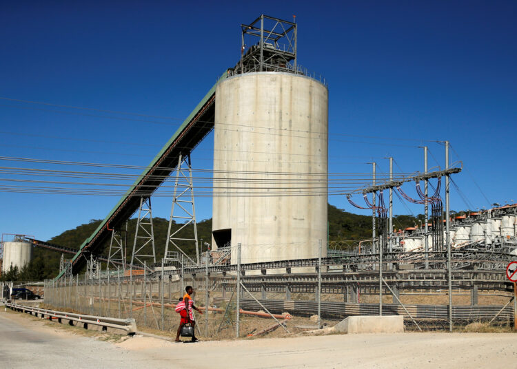 A woman walks past Anglo American Platinum's Unki mine in Shurugwi
