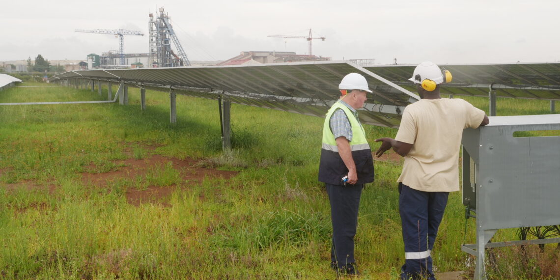 Two employees of the Pan African Resource’s gold mine talk in front of a solar farm used to power the gold mine in Mpumalanga, South Africa, February 1, 2023. Thomson Reuters Foundation/Kim Harrisberg