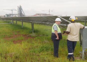 Two employees of the Pan African Resource’s gold mine talk in front of a solar farm used to power the gold mine in Mpumalanga, South Africa, February 1, 2023. Thomson Reuters Foundation/Kim Harrisberg
