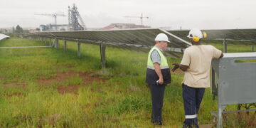 Two employees of the Pan African Resource’s gold mine talk in front of a solar farm used to power the gold mine in Mpumalanga, South Africa, February 1, 2023. Thomson Reuters Foundation/Kim Harrisberg