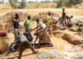 Artisanal miners operate a pump at a small-scale mining site.