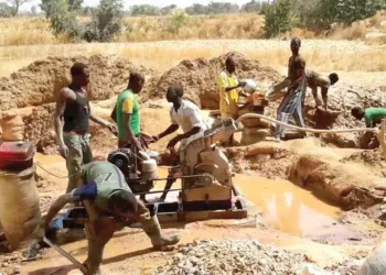 Artisanal miners operate a pump at a small-scale mining site.