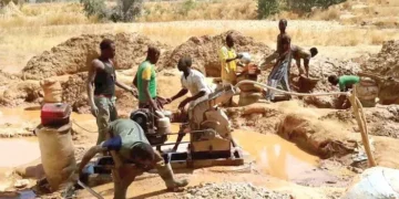 Artisanal miners operate a pump at a small-scale mining site.