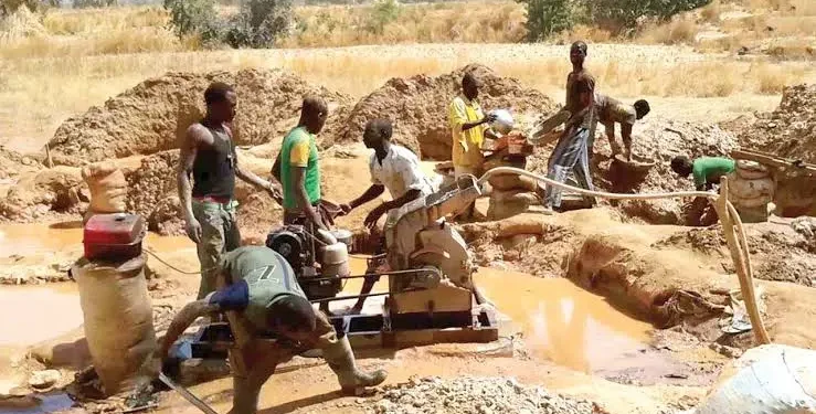 Artisanal miners operate a pump at a small-scale mining site.