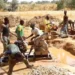 Artisanal miners operate a pump at a small-scale mining site.