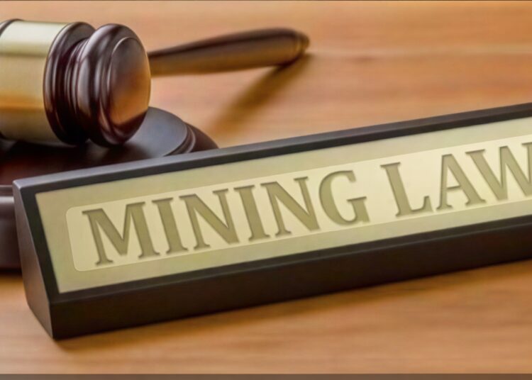 A judge's gavel beside a sign reading "Mining Law".