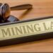A judge's gavel beside a sign reading "Mining Law".
