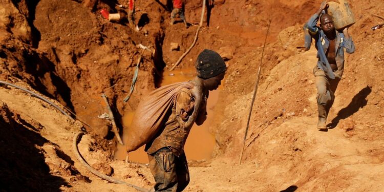 Artisanal miners carrying sacks of ore at a small-scale gold mining site in Zimbabwe