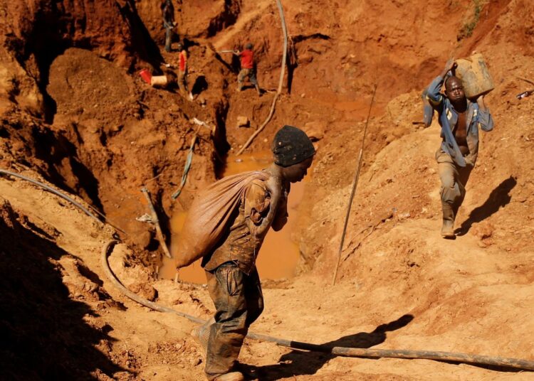Artisanal miners carrying sacks of ore at a small-scale gold mining site in Zimbabwe