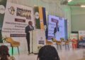 Minister Polite Kambamura speaks at a podium during the Zimbabwe Alternative Mining Indaba, with banners showing the event theme on sustainable development.