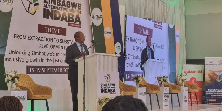 Minister Polite Kambamura speaks at a podium during the Zimbabwe Alternative Mining Indaba, with banners showing the event theme on sustainable development.