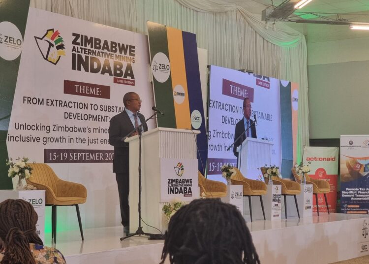 Minister Polite Kambamura speaks at a podium during the Zimbabwe Alternative Mining Indaba, with banners showing the event theme on sustainable development.