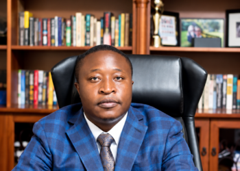 Collins Takunda Mnangagwa, mining and energy executive, seated at a desk in an office with bookshelves