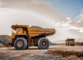 Large dump trucks transport platinum ore for processing at an open-pit mining operation in South Africa.