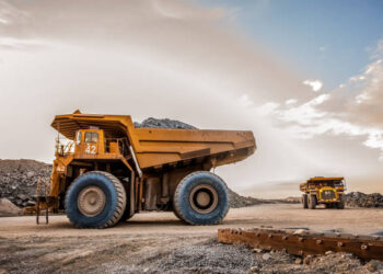 Large dump trucks transport platinum ore for processing at an open-pit mining operation in South Africa.