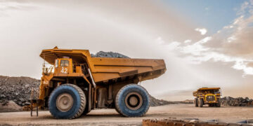 Large dump trucks transport platinum ore for processing at an open-pit mining operation in South Africa.