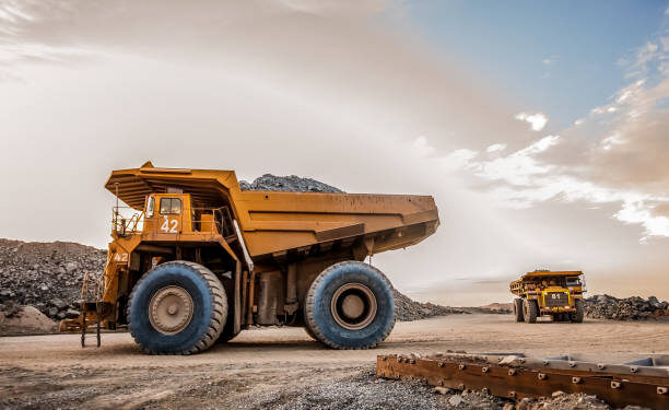 Large dump trucks transport platinum ore for processing at an open-pit mining operation in South Africa.