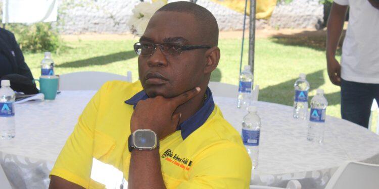 Alfred Chinyere, general manager of Freda Rebecca Gold Mine, seated at an outdoor event with his hand on his chin