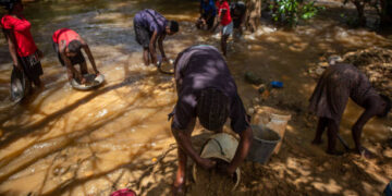 Women and children pan for gold in a river in Banket, Zimbabwe.