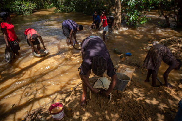 Women and children pan for gold in a river in Banket, Zimbabwe.